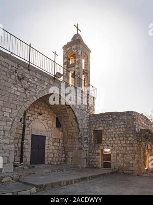 Ingresso e torre campanaria dell'antica chiesa maronita in bar l'am parco nazionale in Israele che mostra l'ingresso anteriore e il campanile a torre illuminata da dietro Foto Stock