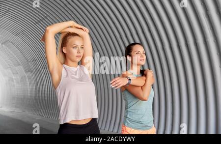 Le donne con fitness trackers stretching all'aperto Foto Stock