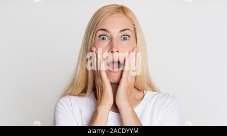 Incredibile! Scioccato donna tenendo le mani sulle guance Foto Stock