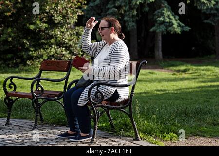 Budapest, Ungheria - 28 Maggio 2019: donna seduta su una panchina nel parco e urlando Foto Stock