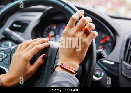 Concetto di scatto: ragazza s le mani sul volante di un automobile, un bracciale con il sogno di iscrizione sulla sua mano. Foto Stock