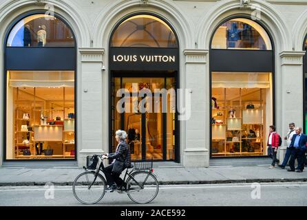 Esterno del Louis Vuitton high-fashion store nel centro storico di Firenze con una vecchia signora passando in bicicletta, Toscana, Italia Foto Stock