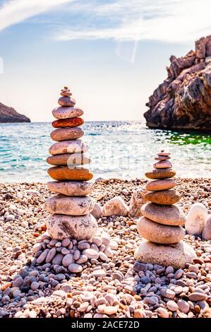 Due torri di pietre piatte sulla spiaggia. Bilanciamento del rock o impilatura di pietra è la disciplina di arte o hobby in cui le rocce sono naturalmente equilibrato sulla parte superiore Foto Stock