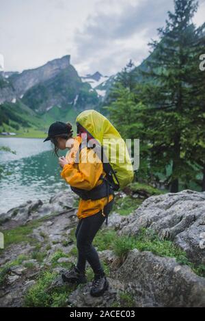 Donna che indossa escursioni gialle sul lago Seealpsee nelle Alpi Appenzell, Svizzera Foto Stock