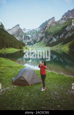 Donna che fotografa in tenda vicino al lago Seealpsee nelle Alpi Appenzell, Svizzera Foto Stock