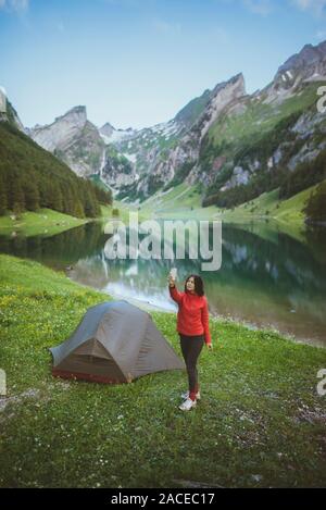 Donna che fotografa in tenda vicino al lago Seealpsee nelle Alpi Appenzell, Svizzera Foto Stock