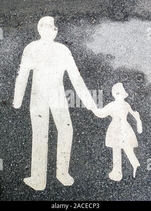 La vernice bianca di adulto e bambino camminando mano nella mano su asfalto nero superficie di un sentiero. Foto Stock