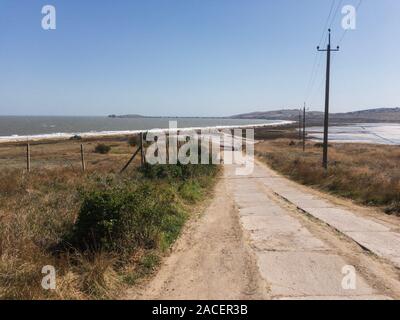 In Crimea desolato paesaggio della strada vuota di Azov mare e sale al lago di fango spazio copia Foto Stock