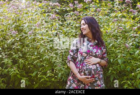 Ritratto di bella donna incinta in giardino Foto Stock