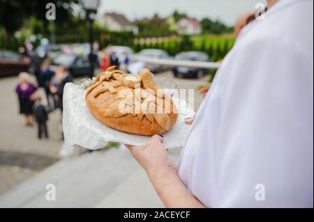 Tradizionale polacco saluto la sposa e lo sposo dai genitori con il pane e il sale. La vodka anche in bicchieri. Foto Stock