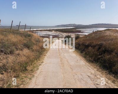Deserto paesaggio della Crimea. Strada vuota, filo spinato e mare in background Foto Stock