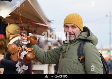 Maturo uomo barbuto con zaino selezionando la kuksa, Finlandese Tradizionale coppa di legno, il mercatino di Natale in piazza Kauppatori a Helsinki, finlan Foto Stock