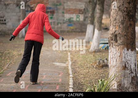 Ragazzina salta in bambini campana gioco disegnato su una strada asfaltata. Foto Stock