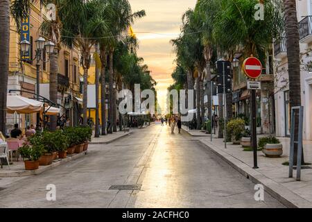 I pedoni una passeggiata lungo la strada principale di Brindisi, Italia, Corso Umberto, come il sole che tramonta sulla città costiera della regione Puglia Foto Stock