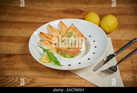 Deliziosa tartare di salmone con avocado. Disposizione con un bicchiere di vino e posate Foto Stock