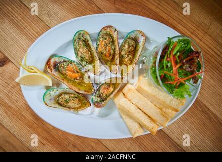 Cozze con salsa di aglio in servizio su piastra bianca nel ristorante Foto Stock