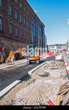 Lavori stradali la costruzione di un nuovo tracciato stradale. Barriere di sicurezza e temporaneo sentiero pedonale in posizione. Uomo con bastone a piedi lungo footway. Foto Stock