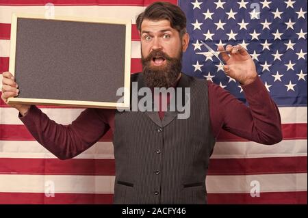 Hipster chic. Barbuto hipster tenendo le forbici e la lavagna in classe. Hipster uomo sulla bandiera americana sfondo. Hipster barbiere insegnamento barbering, copia dello spazio. Foto Stock