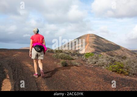 Una donna che cammina fino Montana Los Rodeos a Lanzarote isole Canarie. Foto Stock