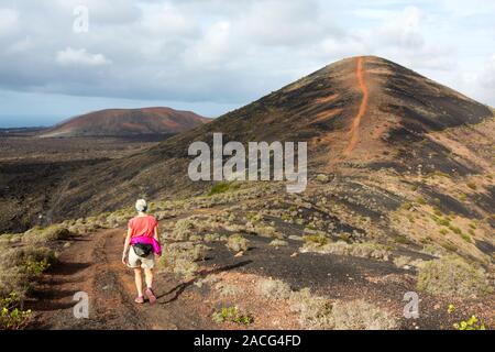 Una donna che cammina fino Montana Los Rodeos a Lanzarote isole Canarie. Foto Stock