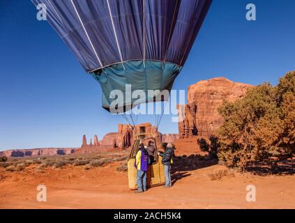 Una mongolfiera in terre nel parco tribale Navajo Monument Valley in Arizona. In fondo è la formazione di roccia chiamato le Tre Sorelle al lef Foto Stock