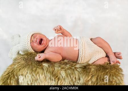 Neonato in costume coniglietto di piangere su un letto di pelliccia Foto Stock