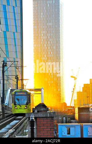 I tram viaggiano su un gradiente ripido oltre il ponte con il sole che tramonta tra blocchi di appartamenti Foto Stock