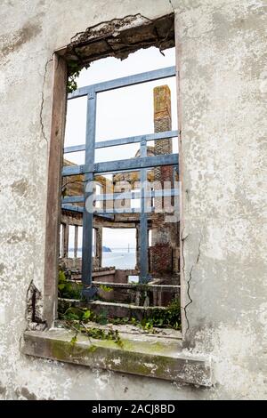 Guardando attraverso una finestra in un vecchio edificio a spiovente sul isola di Alcatraz / carcere vedendo attraverso la costruzione di baia al di là e il Ponte della Baia, Ca Foto Stock