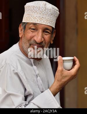 Muscat Oman, Novembre 24rd, 2018: ritratto di un uomo anziano, vestito con il tradizionale abito omani, con la tazzina di caffè. Foto Stock