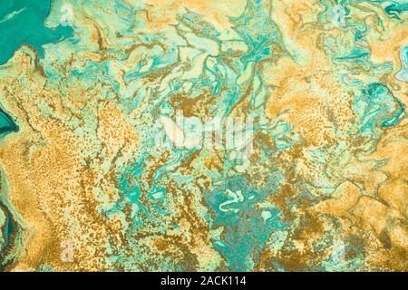 Grani dorati sono casualmente disperse sul libero fluire vernice. Sfondo o texture in colori verde e giallo. Foto Stock