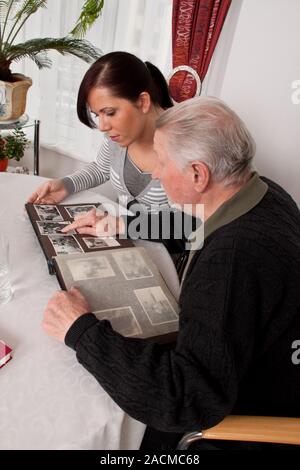 Donna guarda a un album di foto con gli anziani Foto Stock