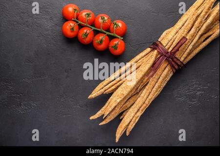 Italiano tradizionale pane di segale grissini e ciliegia su sfondo scuro. Close up. Spazio di copia Foto Stock