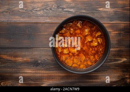 In casa tradizionale gulasch ungherese piatto in un tegame contro uno sfondo di legno Foto Stock