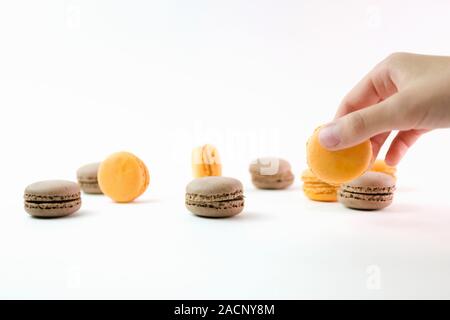 Amaretti su sfondo bianco e la mano che regge uno e colorati di amaretti, il fuoco selettivo. Foto Stock