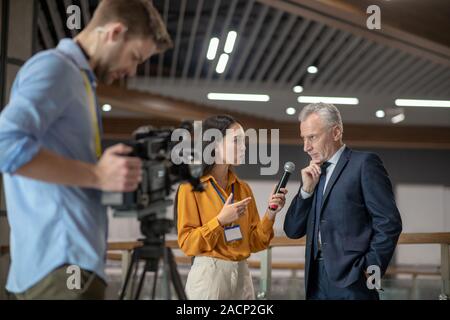 Giovani reporter femmina avente intervista con il famoso uomo d affari Foto Stock