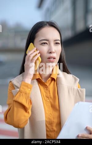 Giovani asiatici pretty woman in beige cardigan cercando gravi Foto Stock