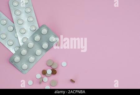 Pillole, compresse e capsule di medicina farmaceutica assortite su sfondo rosa. Vista dall'alto. Disposizione piatta. Spazio di copia. Concetto di medicina. Mucchio di pillole Foto Stock