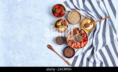 Una sana colazione e la colazione ingredienti, fiocchi d'avena con fichi, lino e semi di Chia, miele. Vista superiore Foto Stock