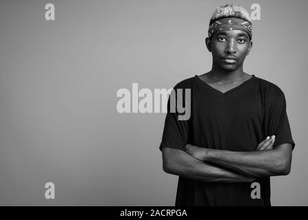 Giovane africano indossando bandana come fascia contro uno sfondo grigio Foto Stock