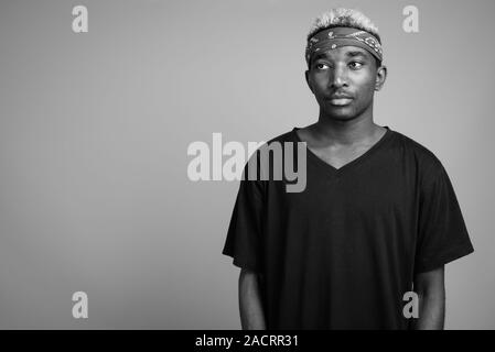 Giovane africano indossando bandana come fascia contro uno sfondo grigio Foto Stock