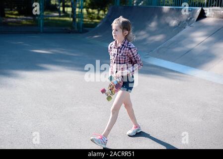 Femmina Skater corse su skateboard a skate park rampa. Giovane donna praticare lo skateboard all'aperto a skate park. Foto Stock