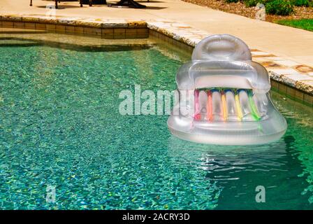 Un vuoto in plastica gonfiabili aria zattera galleggiante in un gunite piscina su un luminoso giorno di estate con spazio di copia Foto Stock