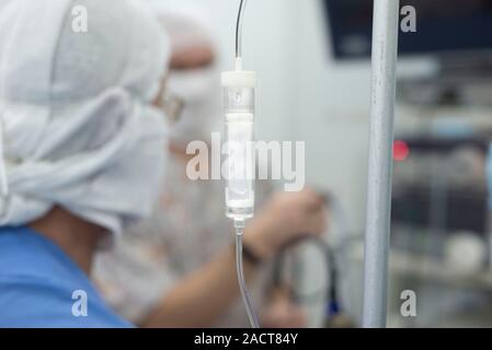 Sistema di infusione intravenosa, nel fuoco. In background, i medici sono di sfocatura. La disintossicazione. Condizioni per una sterile in sala operatoria. Resuscita Foto Stock