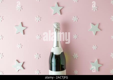 Vista superiore della bottiglia di champagne contro lo sfondo di pattern fatta di stelle e fiocchi di neve. Celebrazione del concetto. Foto Stock