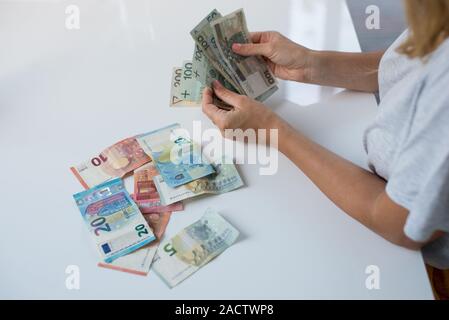 Donna che mantiene Polski Polish Zloty PLN e le banconote in euro in mani. Euro denaro e Polski Polish Zloty PLN in un womans mani su uno sfondo bianco. Di euro in Polonia. Foto Stock