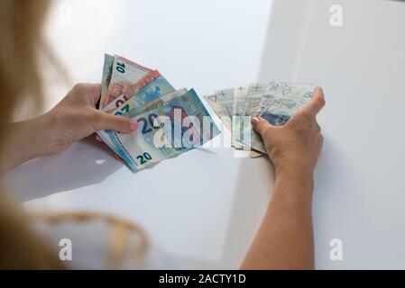 Donna che mantiene Polski Polish Zloty PLN e le banconote in euro in mani. Euro denaro e Polski Polish Zloty PLN in un womans mani su uno sfondo bianco. Di euro in Polonia. Foto Stock