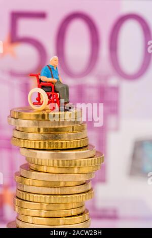 Una donna su una sedia a rotelle su un mucchio di soldi Foto Stock