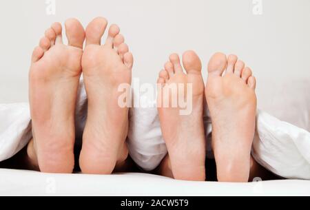 Coppia di piedi nel letto Foto stock - Alamy