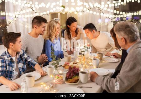 Celebrazione e concetto di famiglia - uomo felice soffiando candele sulla torta di compleanno a cena a casa Foto Stock