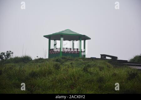 Il famoso passo concreto, gazebo, pavilion di Cherrapunjee eco park con 1/3 di un muro di mattoni, pilastri e tetto in pietra e percorso verde erbe e nebbioso sky Foto Stock